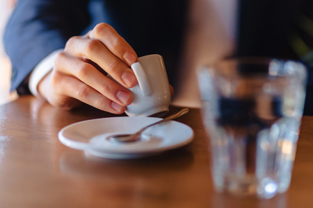 espresso coffee cup in stylish men's hand, morning coffee at cafe with copy space