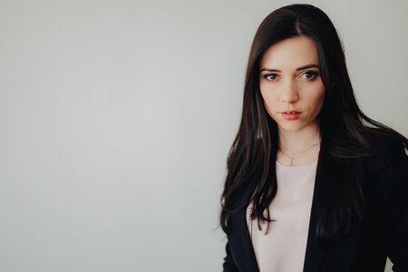 Young attractive emotional girl in business-style clothes on a plain white background in an office or audience aloneの写真素材