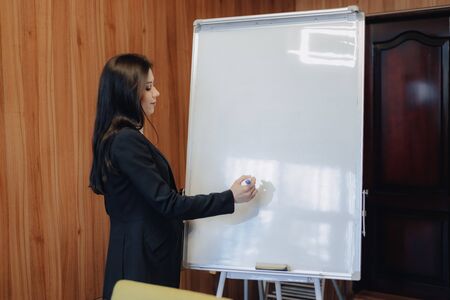 young emotional attractive girl in business-style clothes working with flipchart in a modern office or audience aloneの写真素材