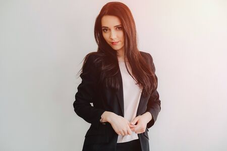 Young attractive emotional girl in business-style clothes on a plain white background in an office or audience aloneの写真素材