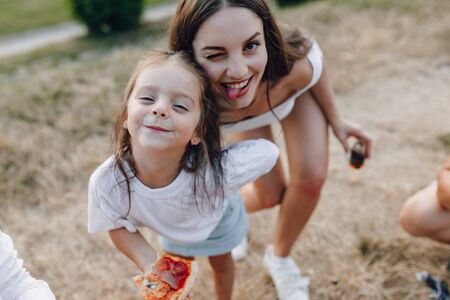 little girl having fun at picnic, eating pizza, drinks, summer and lawnの写真素材