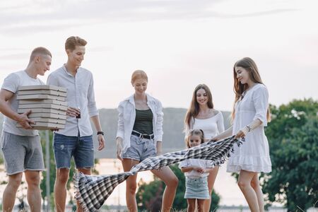 picnic friends with pizza and drinks, warm sunny day, sunset, company, fun, couples and mom with...