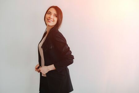 Young attractive emotional girl in business-style clothes on a plain white background in an office or audience aloneの写真素材
