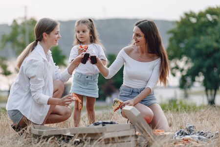 little girl having fun at picnic, eating pizza, drinks, summer and lawnの写真素材