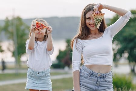 mom and daughter playing with pizza in nature at sunsetの写真素材
