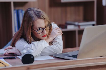 Cozy stylish woman works at a laptop desk in a modern officeの写真素材