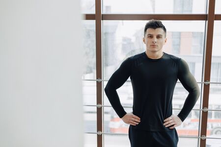 attractive sporty guy by the window. athlete posing near spacious windows. gym and sports. sunny.の写真素材