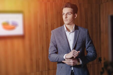 stylish guy in jacket at modern office on simple wooden backgroundの写真素材