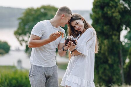 couple eating pizza and drinking in nature at sunsetの写真素材