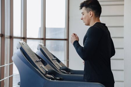 stylish guy in the gym is training on the treadmill. Healthy Lifestyle. wellness.の写真素材