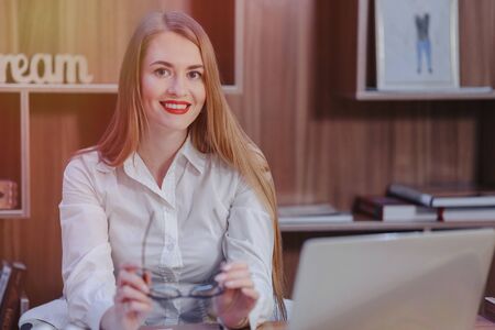 Cozy stylish woman works at a laptop desk in a modern officeの写真素材