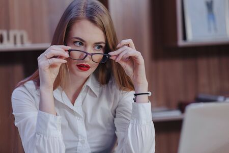 Cozy stylish woman works at a laptop desk in a modern office