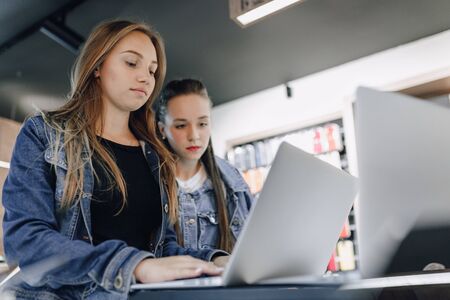 young attractive girls in an electronics store use a laptop at an exhibition. concept of buying...