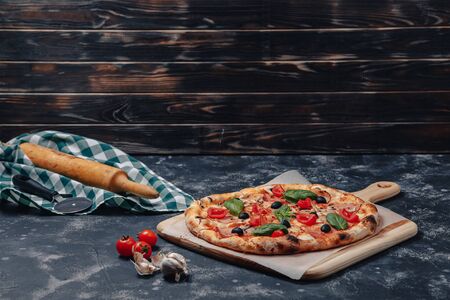delicious Neapolitan pizza on a blackboard with cherry tomatoes, free space for textの写真素材