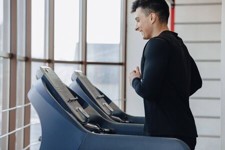 stylish guy in the gym is training on the treadmill. Healthy Lifestyle. wellness.の写真素材