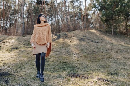young attractive stylish girl on nature on forest background with phone on a sunny day. outdoor holidays and dependence on technology, internet.の写真素材