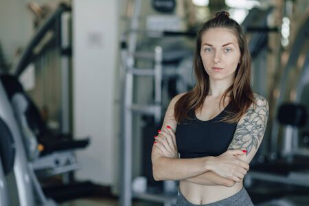 Attractive athletic girl stands on the background of simulators in the gym. healthy lifestyle and...