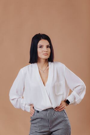 attractive stylish young girl in business attire posing on cream background in studio. concept of stylish clothes and sophistication.の写真素材