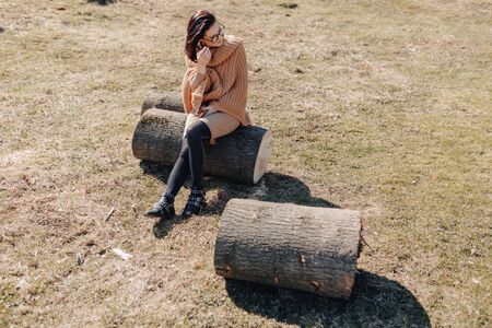 young attractive stylish girl on nature on forest background with phone on a sunny day. outdoor holidays and dependence on technology, internet.の写真素材