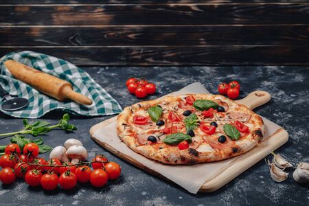 delicious Neapolitan pizza on a blackboard with cherry tomatoes, free space for textの写真素材
