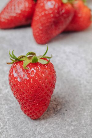 juicy strawberries poured out chaotically on a concrete light background. delicious fruits in summer season. natural products and natural resources. simple picture.の写真素材
