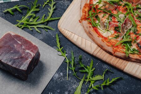 mouth-watering Neapolitan pizza on a blackboard with various delicious ingredients, free space for textの写真素材