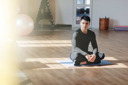 attractive sports guy doing yoga. sun room and shadows. gym and sports. healthy.の写真素材