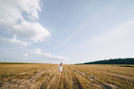pretty woman with blond long hair in a straw hat in a field at sunset. summer, farming, nature and fresh air. sunny.の写真素材