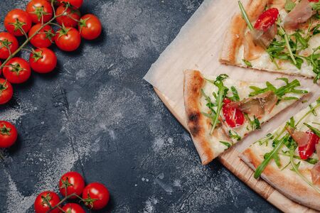 delicious Neapolitan pizza on a blackboard with cherry tomatoes, free space for textの写真素材