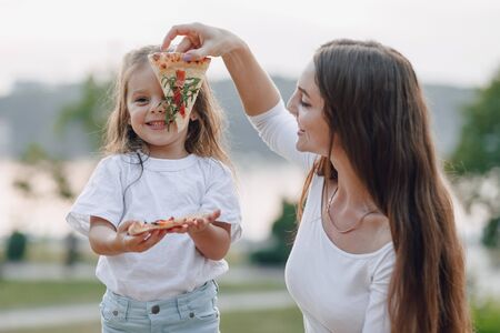 mom and daughter playing with pizza in nature at sunsetの写真素材