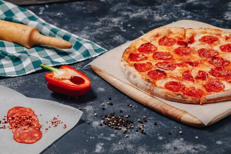 mouth-watering Neapolitan pizza on a blackboard with various delicious ingredients, free space for textの写真素材