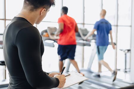 young guy trainer takes notes in the gym. personal trainer for sports. gym and sports.の写真素材