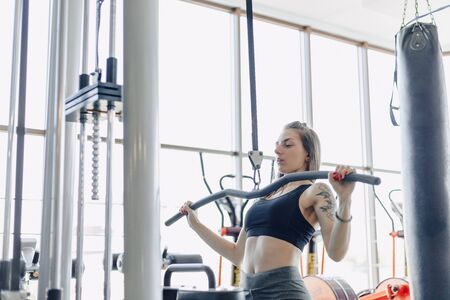attractive athletic girl trains shoulders in simulator. view of the back muscles. healthy lifestyle and wellness.の写真素材