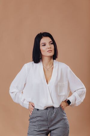 attractive stylish young girl in business attire posing on cream background in studio. concept of stylish clothes and sophistication.の写真素材