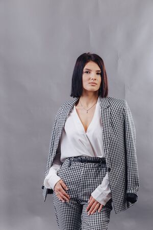 attractive stylish young girl in business clothes posing on dark background in studio. concept of stylish clothes and sophistication.の写真素材