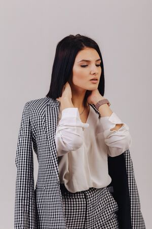 attractive stylish young girl in business clothes posing on light background in studio. concept of stylish clothes and sophistication. simple background.の写真素材