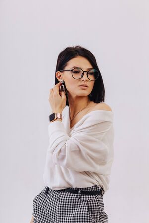 attractive stylish young girl in business clothes posing on light background in studio. concept of stylish clothes and sophistication. simple background.の写真素材