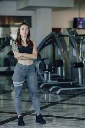 Attractive athletic girl stands on the background of simulators in the gym. healthy lifestyle and wellness.の写真素材