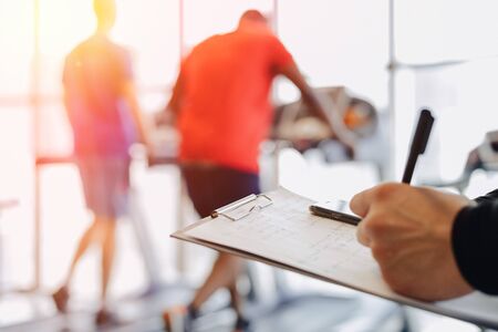 young guy trainer takes notes in the gym. personal trainer for sports. gym and sports.の写真素材