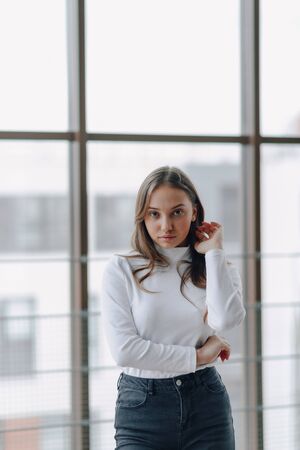 young attractive girl on the background of the window shows different emotions and mood. girl on a light background indoors.の写真素材