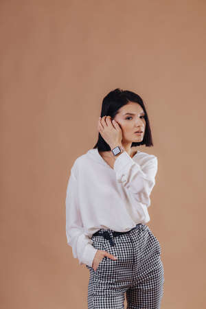 attractive stylish young girl in business clothes posing on light background in studio. concept of stylish clothes and sophistication. simple background.の写真素材