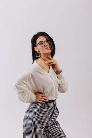 attractive stylish young girl in business clothes posing on light background in studio. concept of stylish clothes and sophistication. simple background.の写真素材