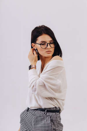 attractive stylish young girl in business clothes posing on light background in studio. concept of stylish clothes and sophistication. simple background.の写真素材