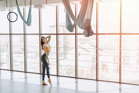 Young attractive fitness girl sitting on chair near the window on the background of a wooden wall, resting on yoga classes at gymの写真素材