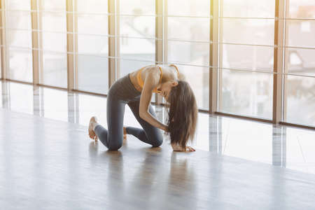 Young attractive fitness girl sitting on chair near the window on the background of a wooden wall, resting on yoga classes at gymの写真素材