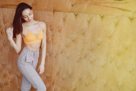 Young attractive fitness girl sitting on chair near the window on the background of a wooden wall, resting on yoga classes at gymの写真素材