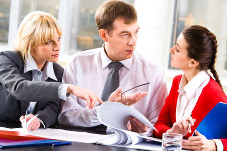 Image of a business lady looking attentively at the speaking business leader while the other woman pointing at some details in the documentの写真素材