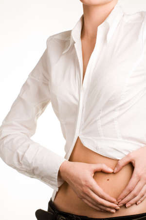Image of woman's hands touching her stomach, heart shaped fingers