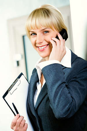 Image of a young attractive businesswoman calling by phone holding the folderの写真素材