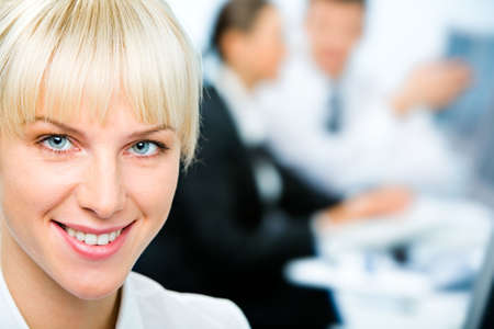 Closeup of smiling businesswomans face on the background of two working business partnersの写真素材